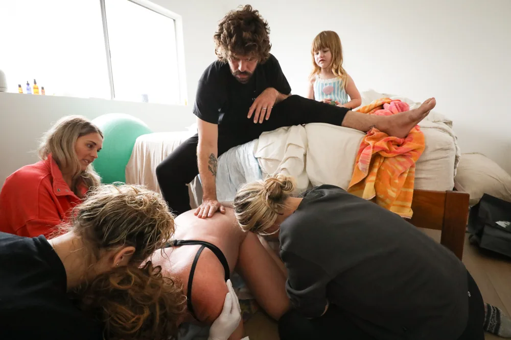 A birth team gathered around a laboring mother at home