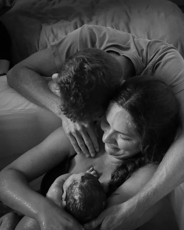 A couple in happy tears holding their newborn, black and white birth photography by Jenn Miller, Orange County