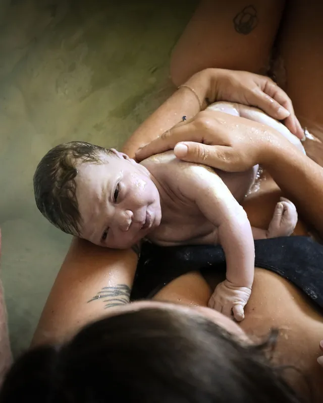 A newborn resting on mom's chest, seen from above in the birth pool, Orange County birth photography by Jenn Miller