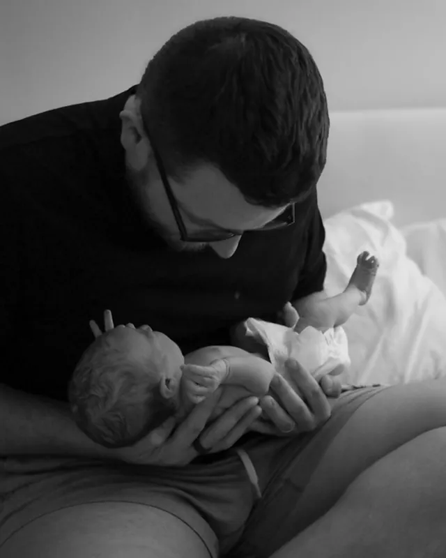 A father cradles his newborn, black and white birth photography by Jenn Miller, Orange County