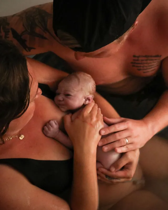 A father leans in as his newborn rests on mom's chest, Orange County birth photography by Jenn Miller
