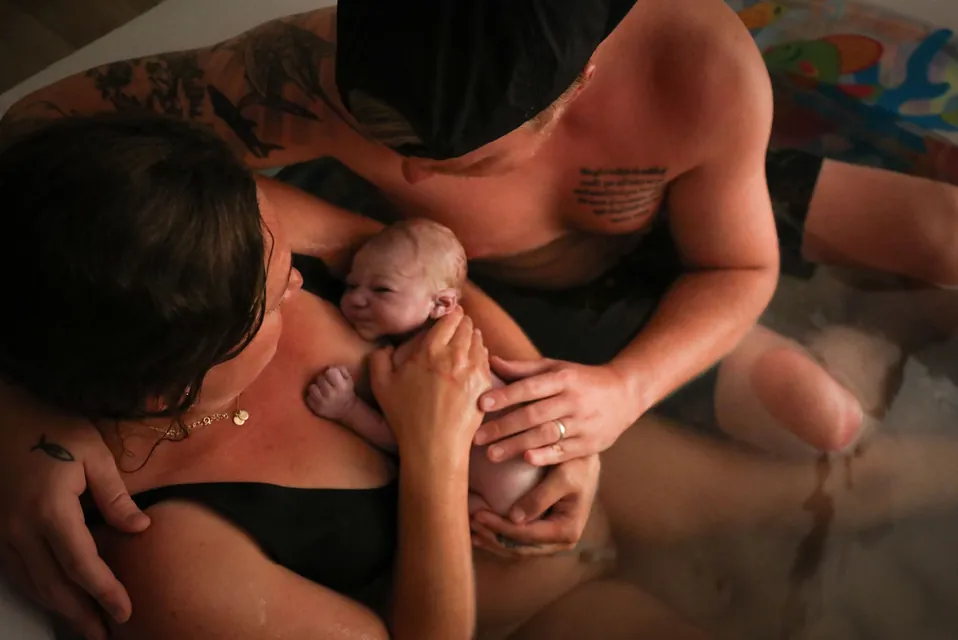 A father leans in as his newborn rests on mom's chest