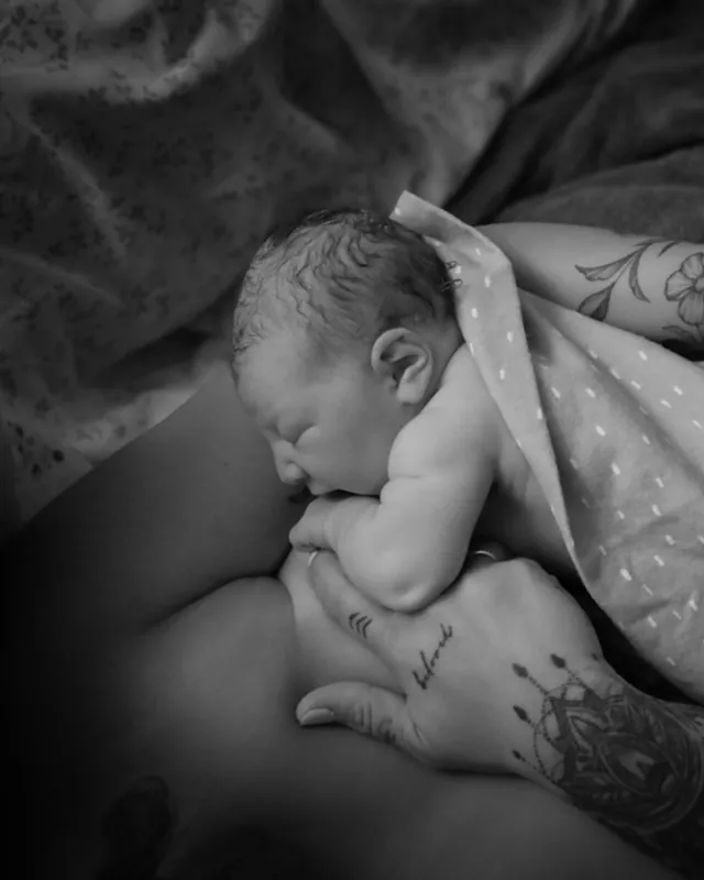 A newborn resting on mom, wrapped in a blanket, black and white birth photography by Jenn Miller, Orange County