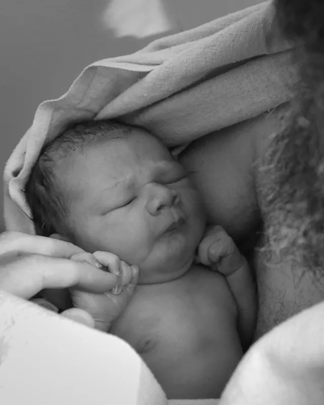 A newborn skin to skin on dad's chest, black and white birth photography by Jenn Miller, Orange County