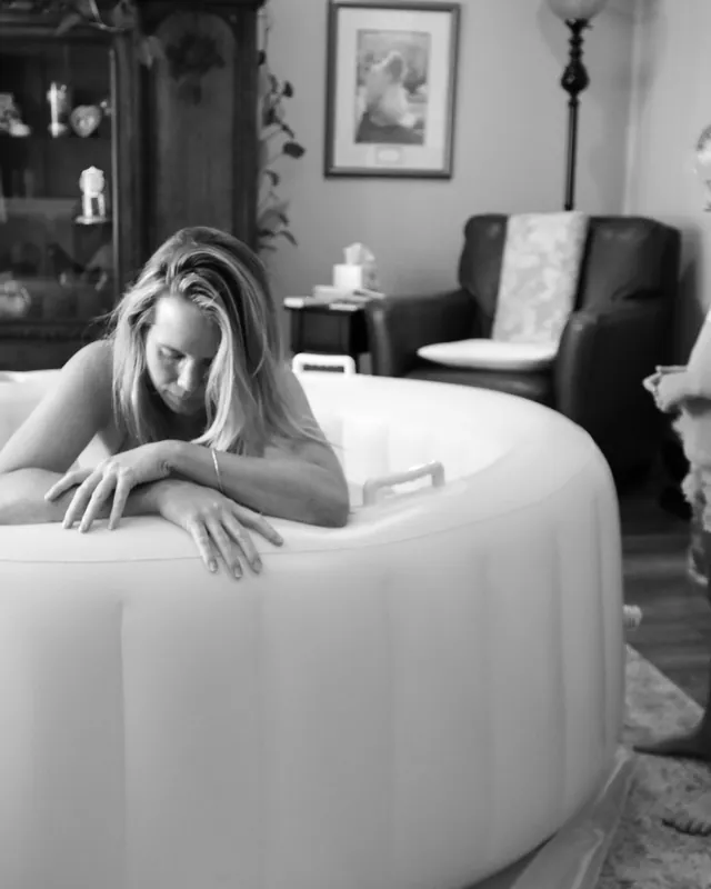 A big sister watches her mother labor in the birth pool, black and white birth photography by Jenn Miller, Orange County