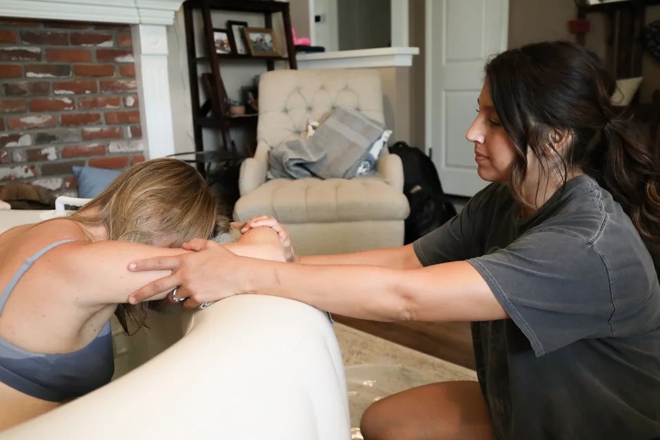 Jenn Miller holding a laboring mother's hands across the birth pool