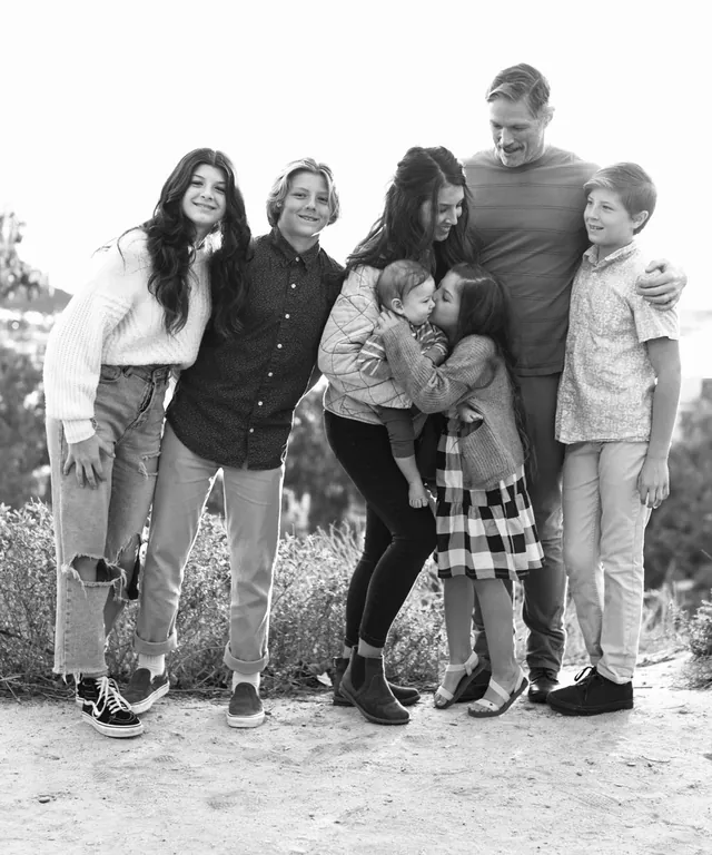 Jenn Miller, her husband and their five children hugging outdoors, in black and white