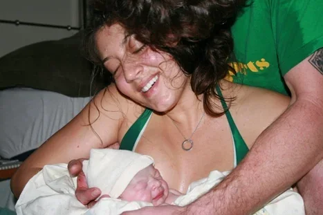 Jenn Miller smiling down at her newborn, moments after giving birth