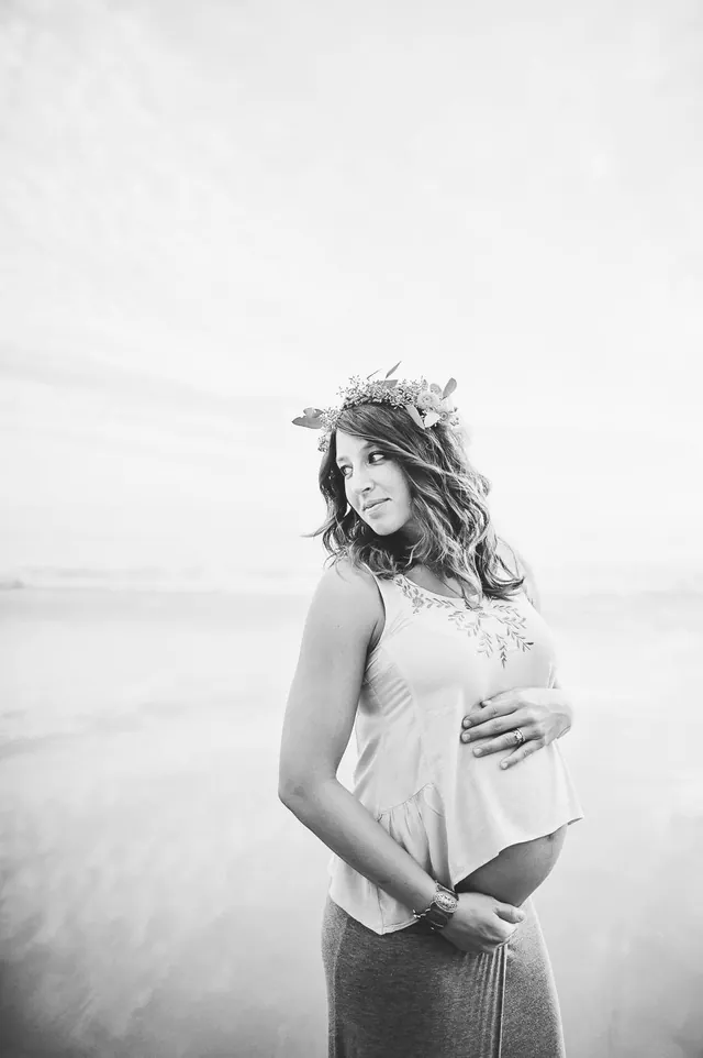 Jenn Miller, pregnant, wearing a flower crown by the ocean, in black and white