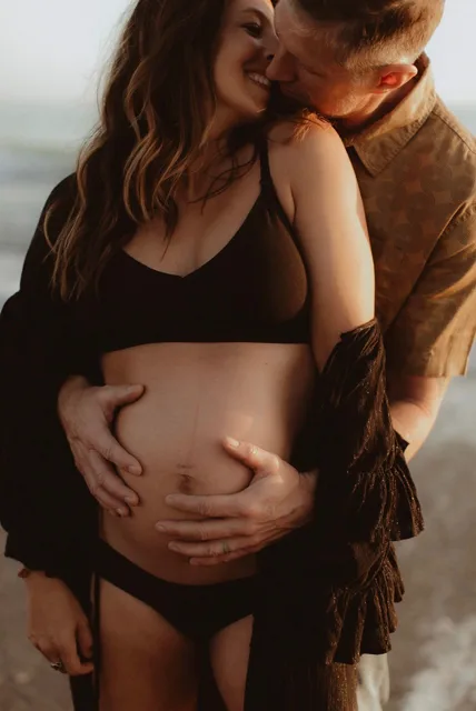 Jenn Miller, pregnant, held by her husband